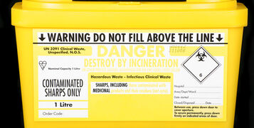 Yellow,Medical,Sharps,Disposal,Box,On,A,Black,Background